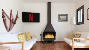 A cozy living room with two white sofas, patterned cushions, a fireplace, a Netflix sign, and a framed picture on the wall. - BEAUTIFUL HOUSE IN TOSSA (Tossa de Mar)