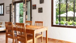 A dining area with a wooden table and chairs, a window with a view of greenery, and wall decorations including signs for Paris, New York, and London. - BEAUTIFUL HOUSE IN TOSSA (Tossa de Mar)