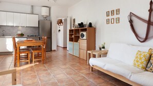 A modern kitchen with white cabinets, a dining table with chairs, a sofa with patterned cushions, and a small side table. - BEAUTIFUL HOUSE IN TOSSA (Tossa de Mar)