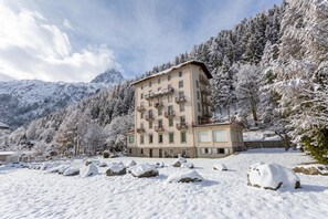 A multi-story hotel with balconies, set in a snowy mountainous area.