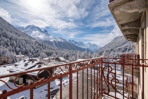 A mountain view with snow-covered buildings and a red balcony railing.
