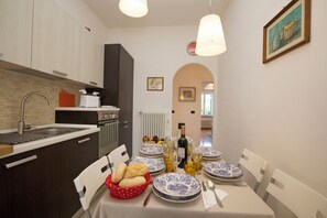 A dining area with a table set for four, a kitchen with modern appliances, and a view into another room.