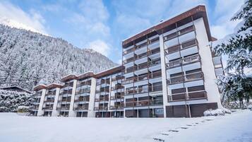 Un hôtel à plusieurs étages, doté de balcons, qui se dresse sur fond de montagnes enneigées.