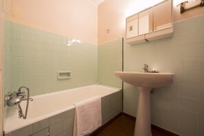 A bathroom with a bathtub, a sink, and a mirror.