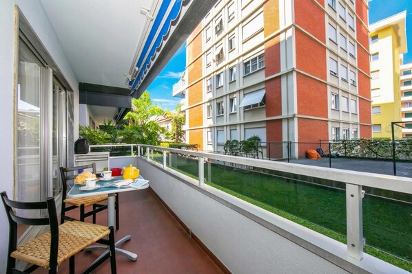 A balcony with a table, chairs, and a view of a multi-story building. - Pool House in Lugano with Shared Garden, Lugano, Switzerland (Lugano)