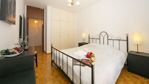 Een slaapkamer met een bed, nachtkastjes, een dressoir, een spiegel en een deur naar een badkamer.