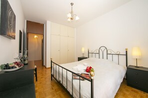 A bedroom with a bed, bedside tables, a nightstand, a dresser, a mirror, and a door leading to a bathroom. - Pool House, Lugano, Switzerland (Lugano)