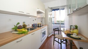 Een compacte keuken met witte kasten, een houten aanrechtblad en een eethoek met een tafel gedekt voor twee personen.