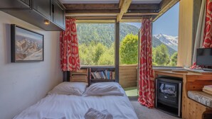 Ein Schlafzimmer mit Bett, Bücherregal, Kamin und einem Fenster mit Vorhängen.
