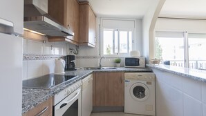 Ett kompakt kök med inbyggd ugn, mikrovågsugn och tvättmaskin.