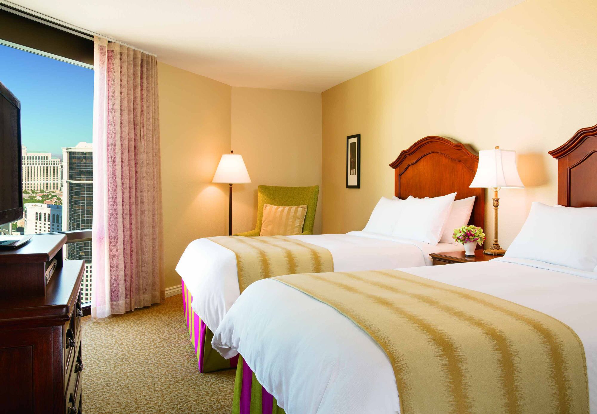 Une chambre d’hôtel avec deux lits, un bureau et une vue sur la ville.