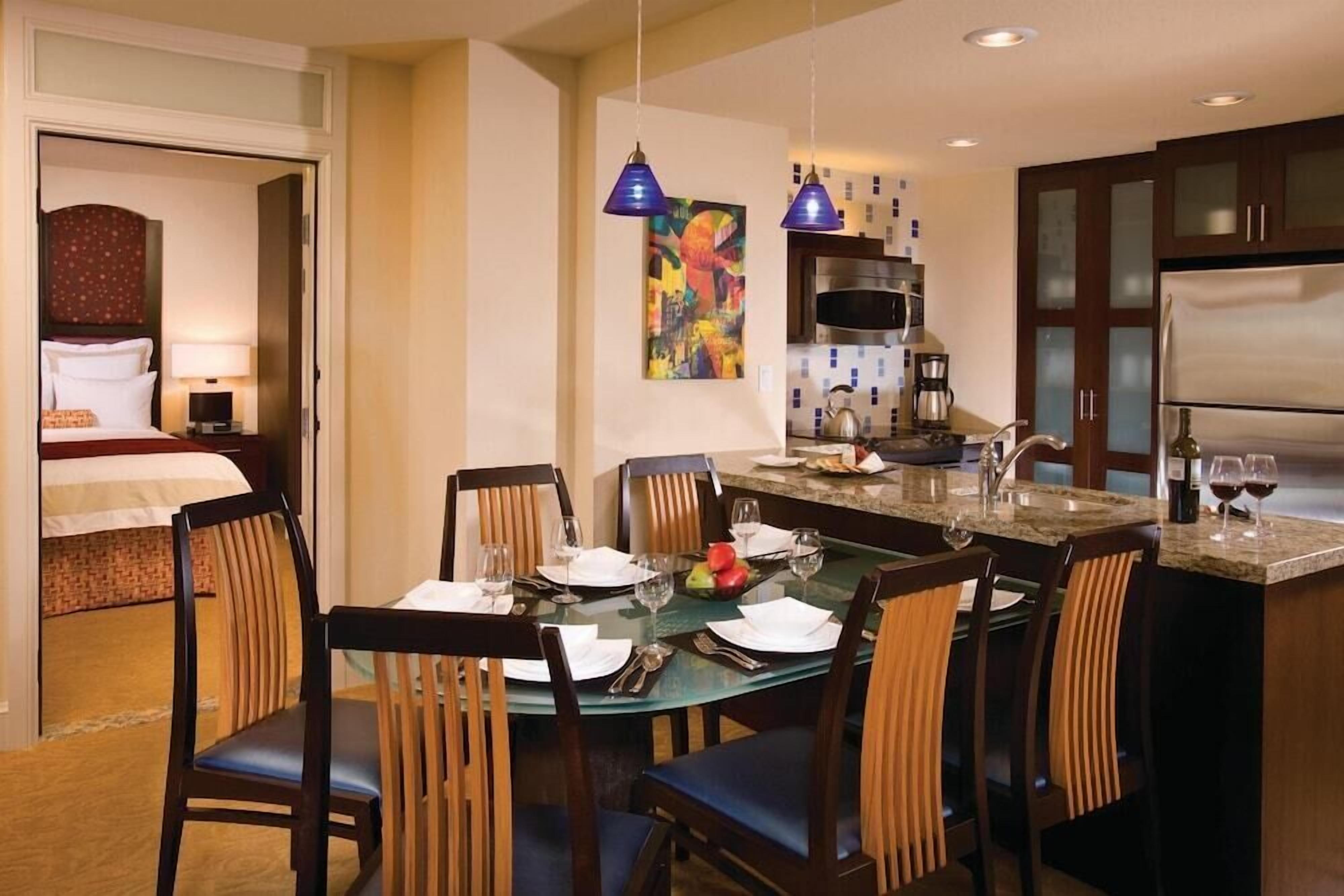 A hotel room with a dining area, a kitchen, and a separate bedroom.