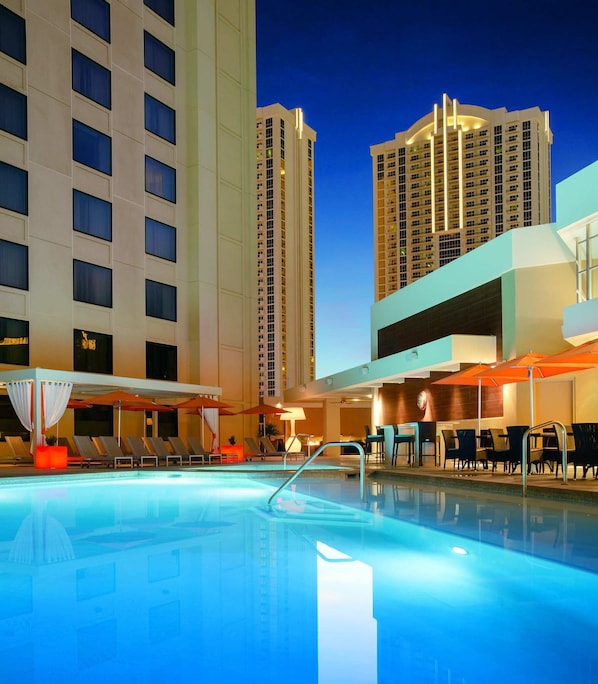 A swimming pool with lounge chairs and umbrellas, surrounded by high-rise buildings. - Marriott's Grand Chateau (Las Vegas)