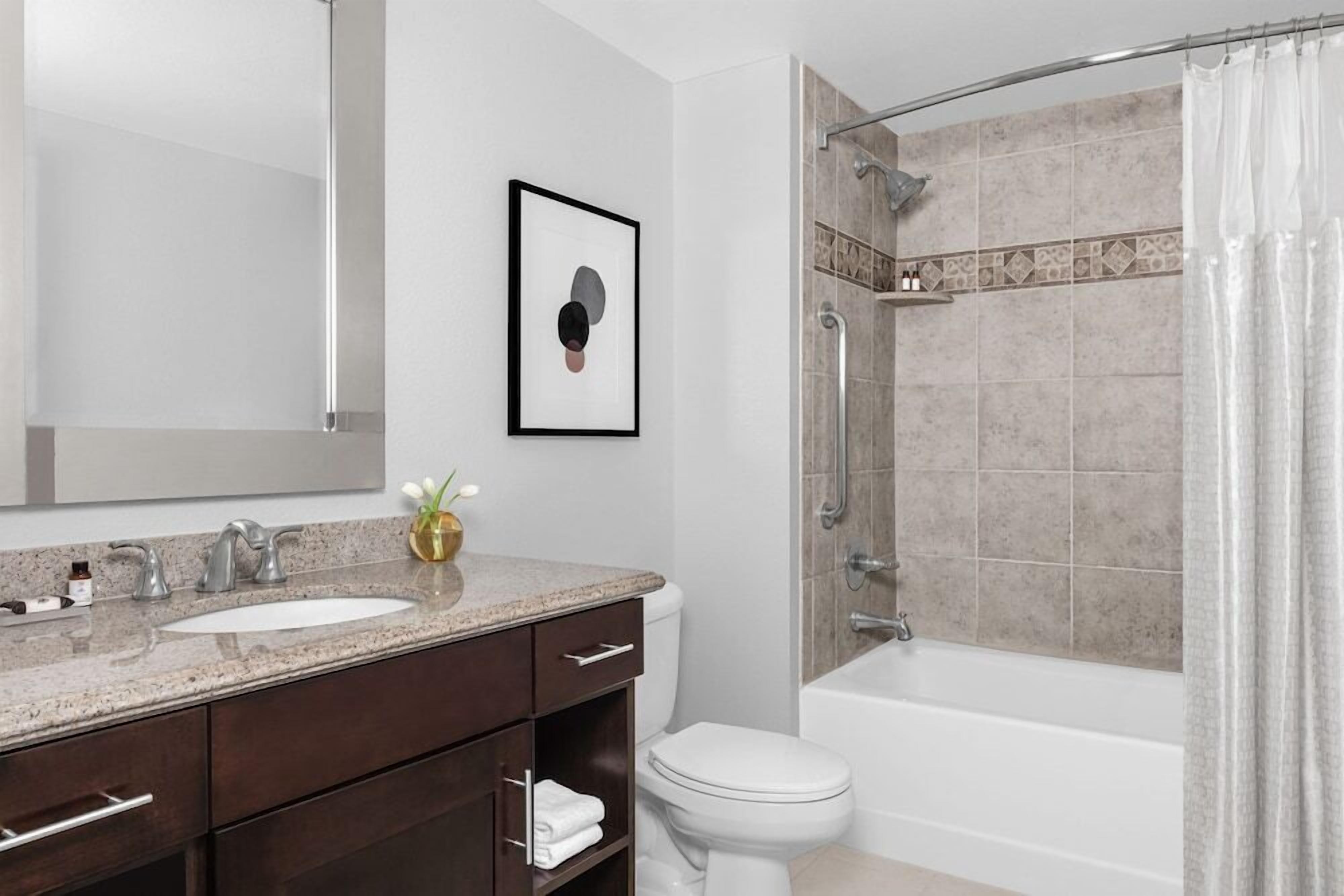 A modern bathroom with a sink, mirror, toilet, shower, and bathtub.