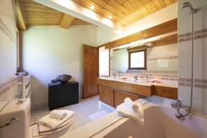 A modern bathroom with a wooden ceiling, a large bathtub, a vanity with a mirror, and a shower. - Chalet du Golf618 Family retreat for 9 next to Ski lifts, Chamonix, France (Chamonix)