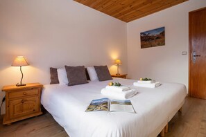 A neatly made bed with pillows, a bedside lamp, a book, and a folded towel on the bed. - Chalet du Golf618 Family retreat for 9 next to Ski lifts, Chamonix, France (Chamonix)