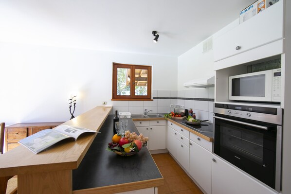 A modern kitchen with white cabinets, a black countertop, a microwave, and an oven. - Chalet du Golf618 Family retreat for 9 next to Ski lifts, Chamonix, France (Chamonix)