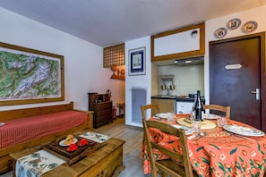 A cozy room with a dining table set for two, a wooden bench, and a small kitchen area with a refrigerator and a sink. - Cham Sud E434 Walk to Aiguille du Midi Balcony, Chamonix, France (Chamonix)