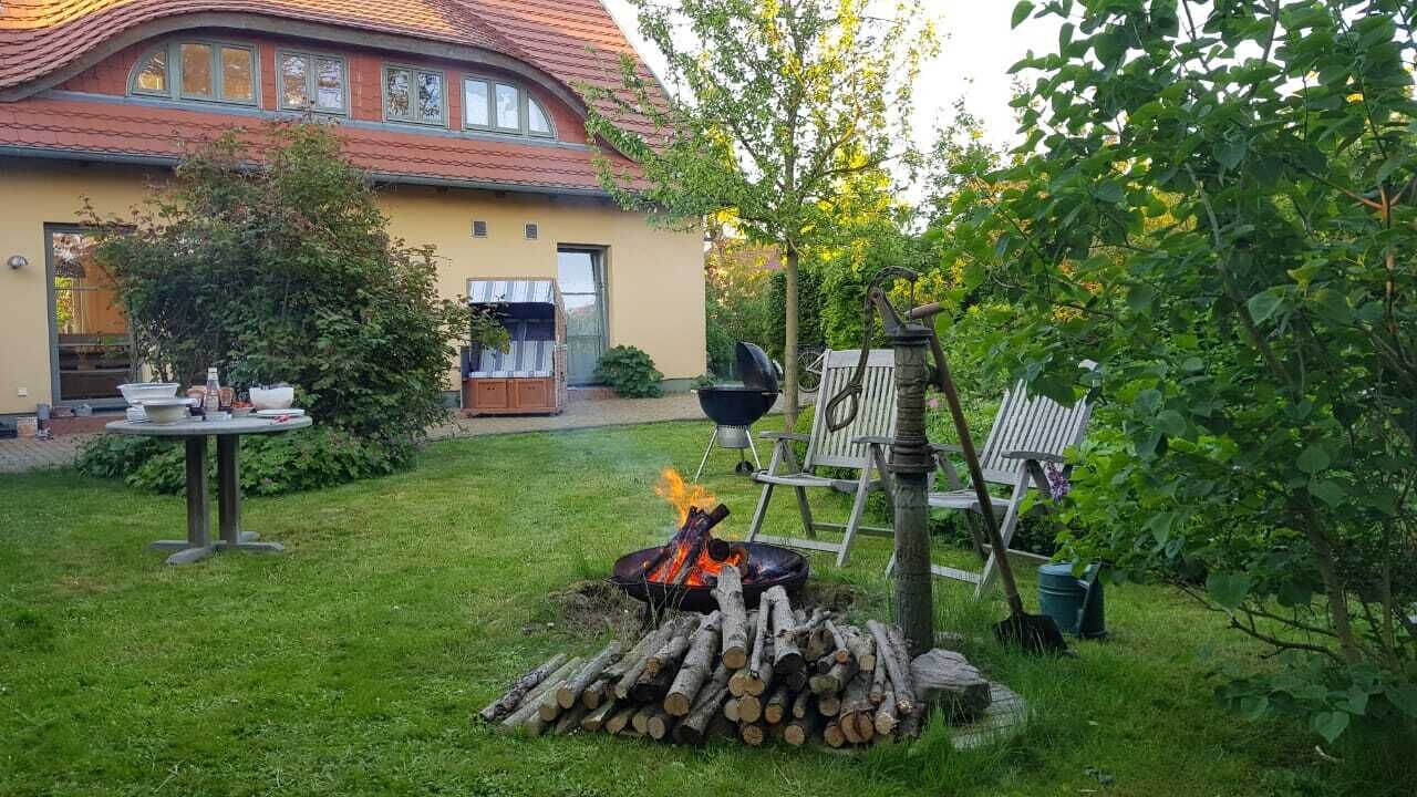 A backyard with a fire pit, a table with dishes, and a house in the background.
