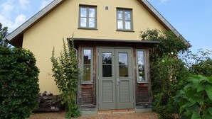 Une maison à deux étages, avec un toit à pignon, une porte d’entrée dotée d’un petit porche et le numéro « 2a » affiché sur la porte.