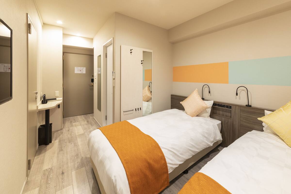 A hotel room with two beds, a bathroom, and a small sitting area.