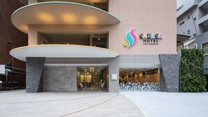 En modern hotellentrén med ett välvt tak, en glasfasad och en logotyp för Sarasa Hotel.