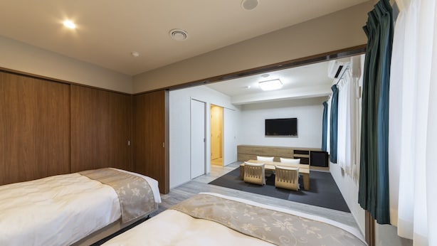 Ett hotellrum med två sängar, ett skrivbord och en tv.