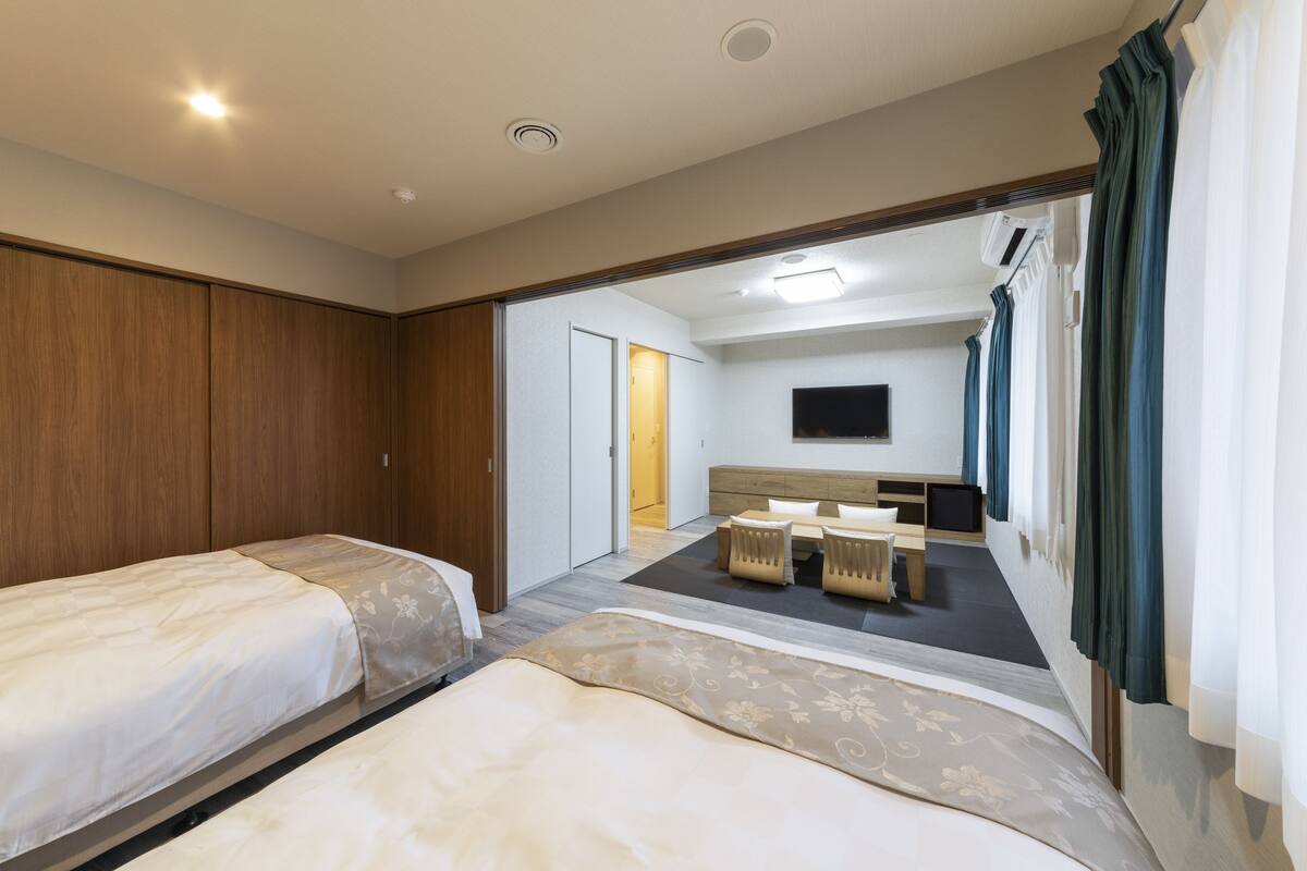 A hotel room with two beds, a desk, and a television.
