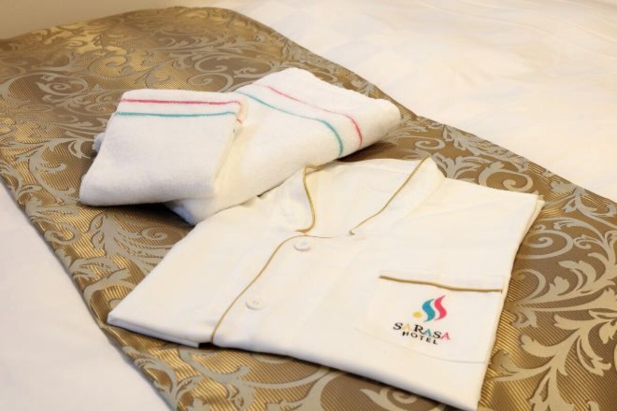 Neatly folded white robes with colorful trim and a logo on a patterned bedspread.