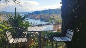 An outdoor patio with a table and two chairs, overlooking a scenic view of a river and a cityscape. - La Bâtie, La Tour: duplex apartment. (Vienne)