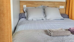 A bed with a patterned bedspread, two pillows, and a folded towel. - La Bâtie, La Tour: duplex apartment. (Vienne)