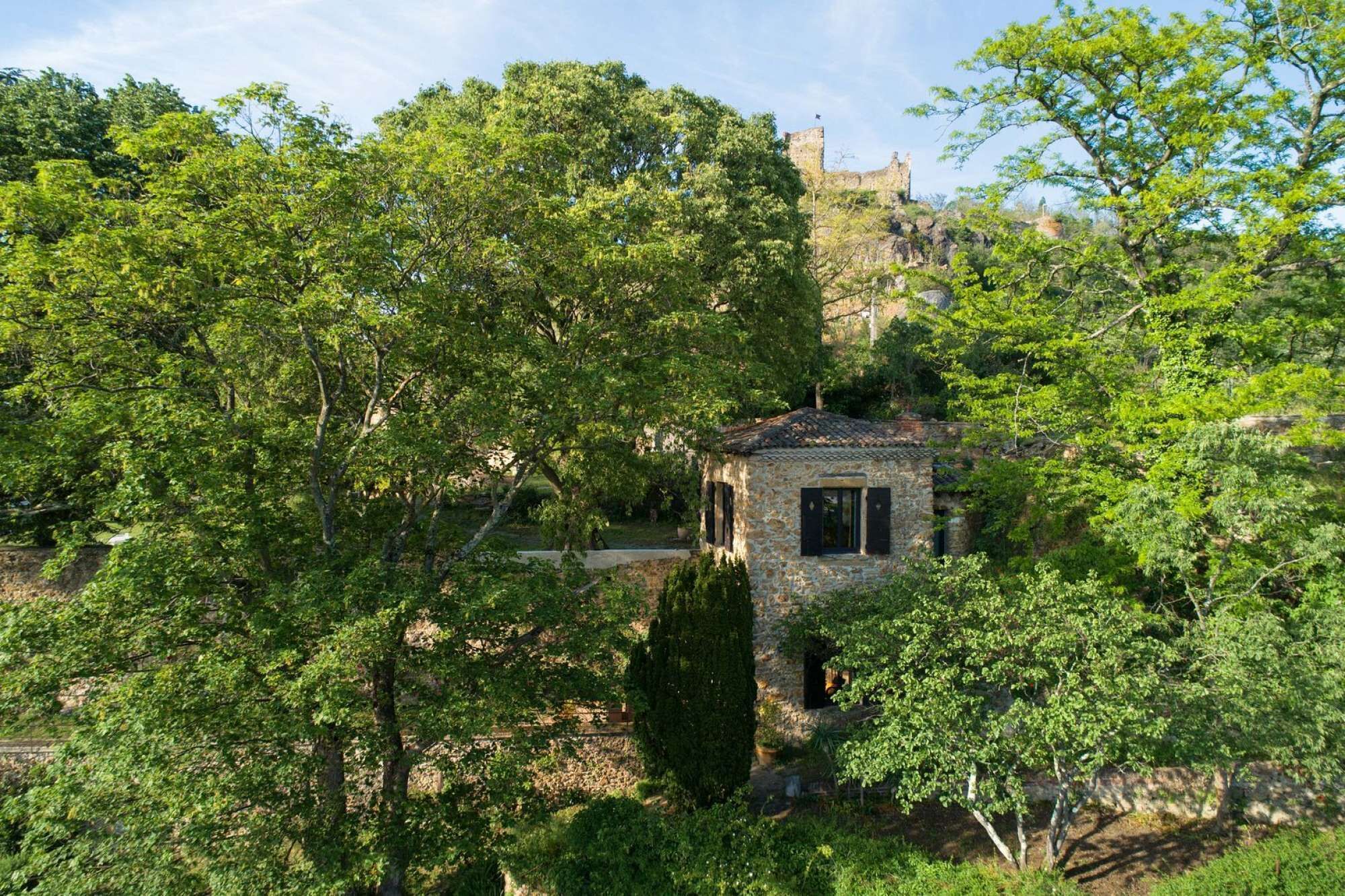 Un bâtiment en pierre entouré d’une végétation luxuriante.