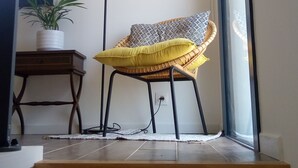 Una escalera conduce a una habitación con una silla de mimbre, una lámpara de pie y una planta en maceta.
