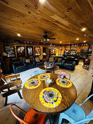 A cozy interior with a wooden ceiling, a round table with colorful centerpieces, and a bar area in the background.