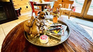 A cozy room with a wooden interior, a round wooden table with a tray of items, a teddy bear sculpture, and a poster of Batman on the wall. - Blue Ridge Castaway Cabin on The Toccoa River (Blue Ridge)