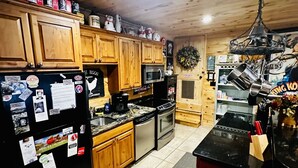 A kitchen with wooden cabinets, a refrigerator, a microwave, a stove, and a sink. - Blue Ridge Castaway Cabin on The Toccoa River (Blue Ridge)