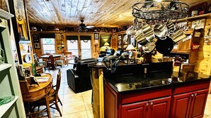 A rustic kitchen with wooden beams, a dining area with a wooden table and chairs, and a red island with cabinets. - Blue Ridge Castaway Cabin on The Toccoa River (Blue Ridge)
