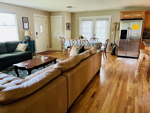A living room with a sofa, coffee table, and dining area with chairs and a table.