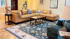 A living room with a sectional sofa, a coffee table, a patterned rug, a cabinet, and framed artwork on the walls. - Great location for visiting the NW. Comfortable 5 bedroom home. (Portland)