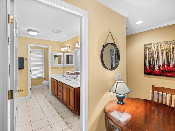 A kitchen with wooden cabinets, a white countertop, and a dining table with a lamp.