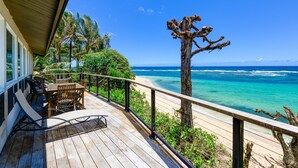A wooden deck with outdoor furniture overlooking a beach and ocean. - Haena Beachfront With Stunning Panoramic Ocean Views TVNC # 5134  (Hanalei, Haena)