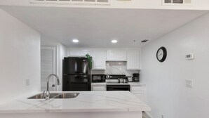 A modern kitchen with white cabinetry, a black refrigerator, a built-in oven, and a sink. -  DOWNTOWN PALM SPRINGS POOLSIDE LOWER  CONDO STEPS TO CASINO   (Palm Springs)