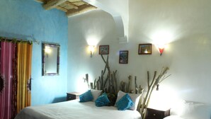 A bedroom with a bed, two nightstands, a mirror, and wall-mounted lights. - Dar Timitar Eco lodge  (Kelâat M'Gouna)