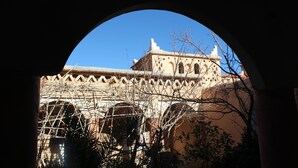 A building with a distinctive arched entrance, a clear blue sky, and a bell tower. - Dar Timitar Eco lodge  (Kelâat M'Gouna)