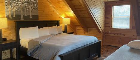 Un dormitori de cabana de fusta amb un llit, taules de nit i una finestra.