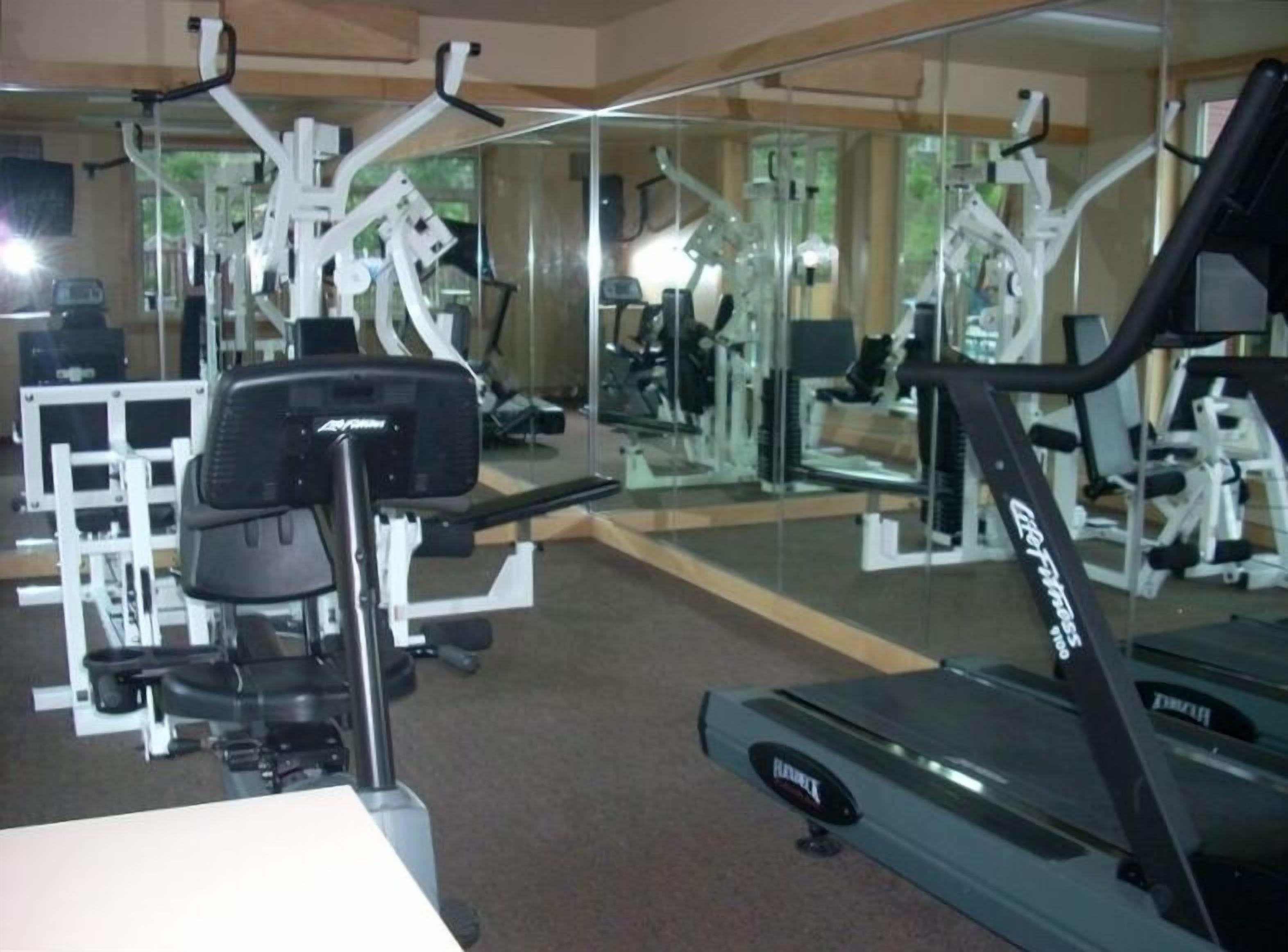 A gym with cardio equipment, weight machines, and mirrors.