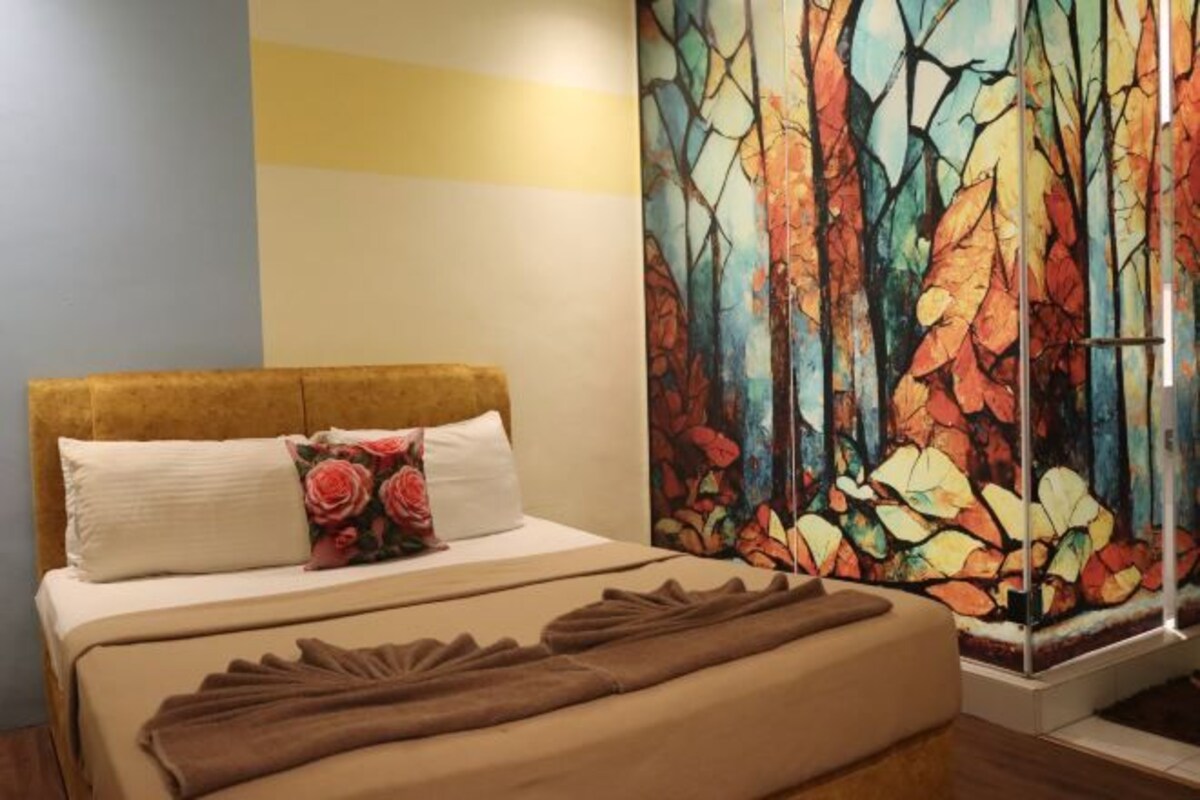 A hotel room with a bed, a painting, and a window.