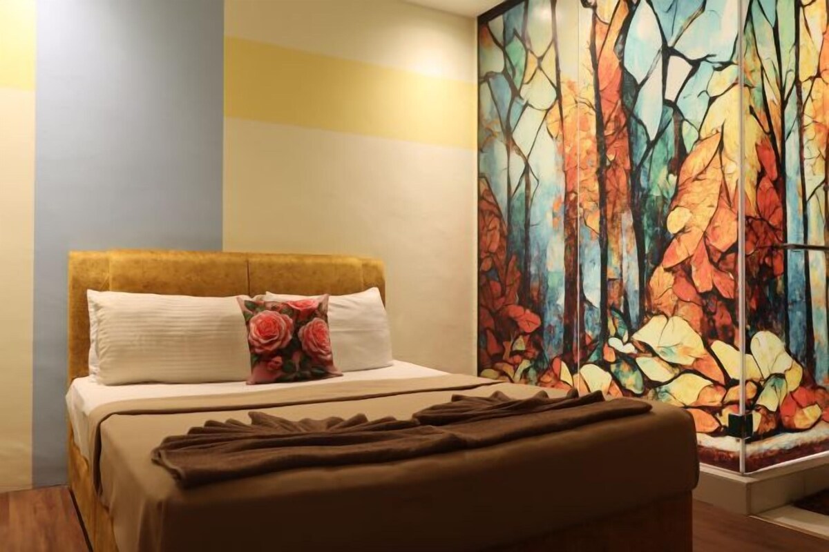 A hotel room with a bed, a painting on the wall, and a window.