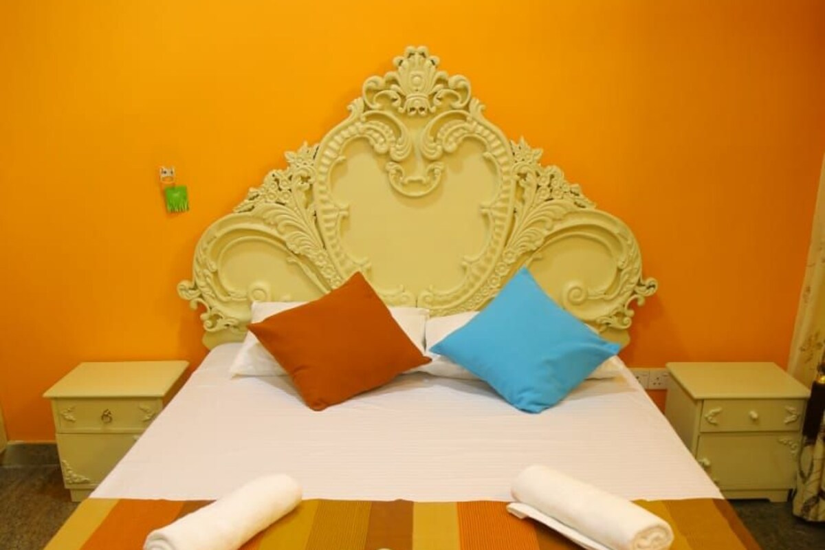 A bed with ornate headboard, two pillows, and rolled towels.