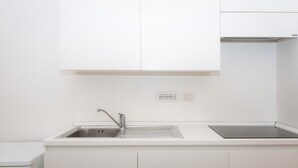 A kitchen with white cabinets, a stainless steel sink, and a built-in stove. - Rental In Rome Arenula Apartment (Rome)